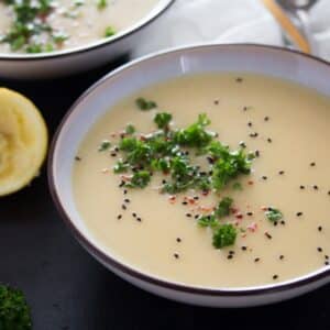 bowl of german kohlrabi soup sprinkled with parsley and seeds.