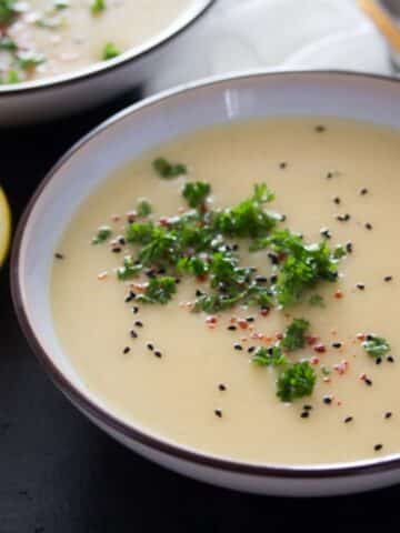 bowl of german kohlrabi soup sprinkled with parsley and seeds.