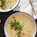 two bowls of creamy soup with potatoes and german turnip sprinkled with parsley.