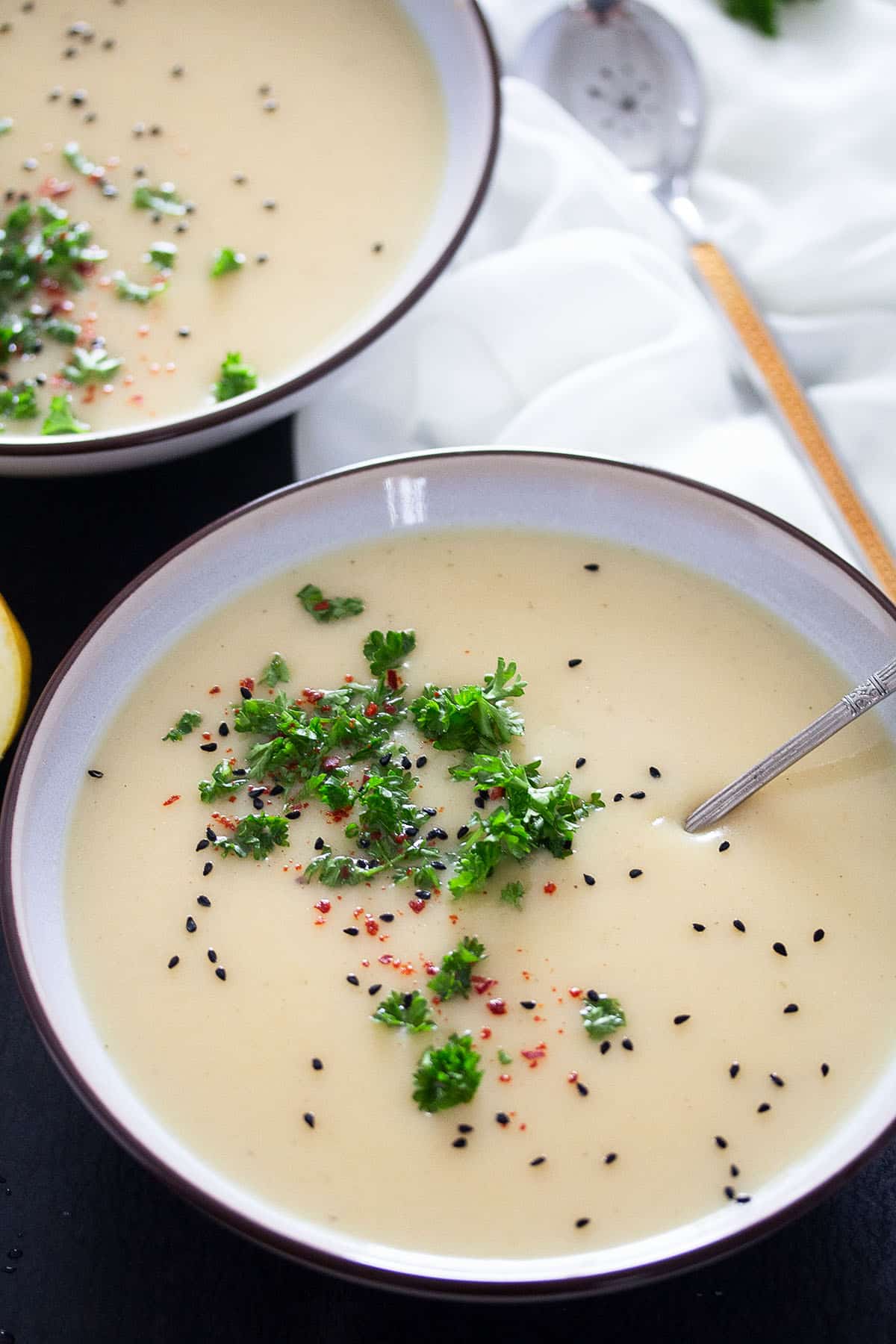 creamy, german kohlrabi soup in a bowl with a spoon in it, another bowl behind.