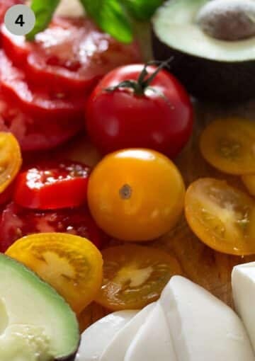 green and red small tomatoes, mozzarella slices and avocado on a cutting board.