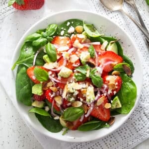 strawberry goat cheese salad with spinach, almonds and avocado on a plate.