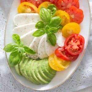 mozzarella tricolore salad with slices of tomato, avocado, and mozzarella on a platter.