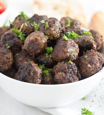 turkish beef meatballs in a white bowl served with bread and tomatoes