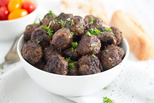 turkish beef meatballs in a white bowl served with bread and tomatoes