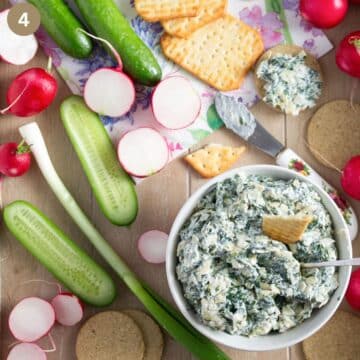 bowl with artichoke spinach dip, raw veggies and crackers.