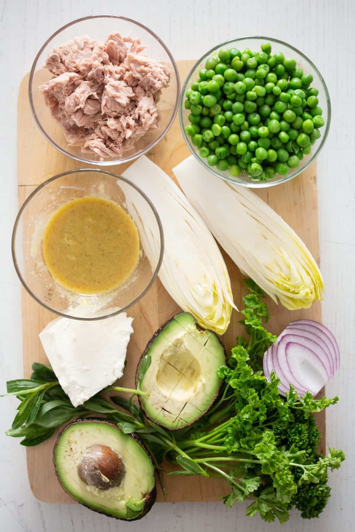 ingredients for tuna feta pea salad on a wooden board.