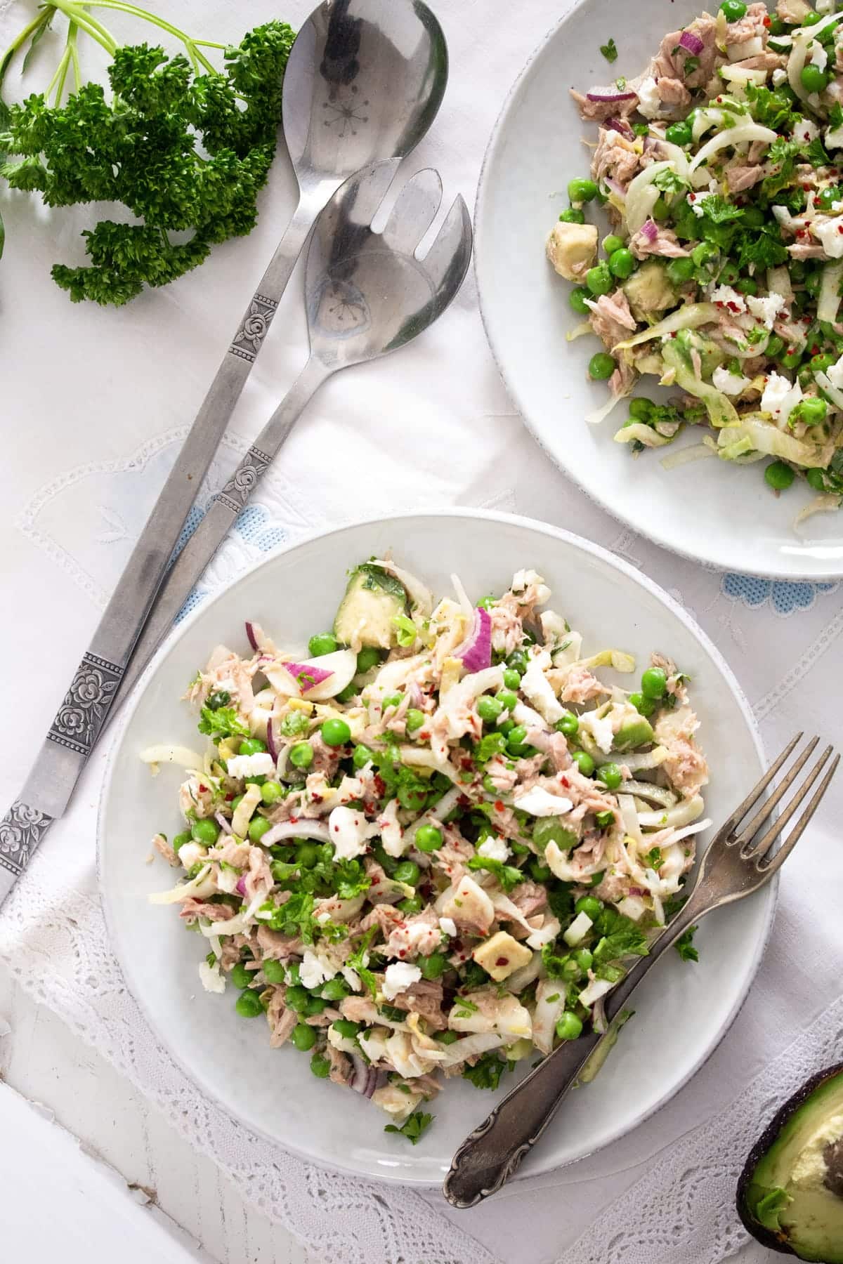 tuna avocado feta salad on plates with salad cutlery beside them.