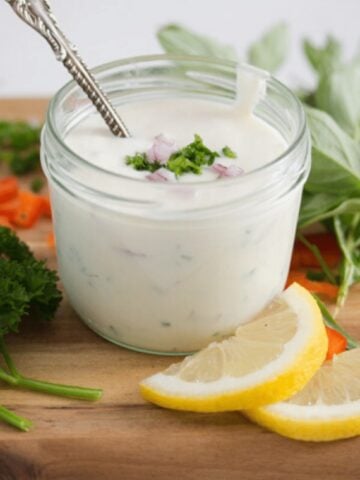 yogurt dressing for salad in a small bowl with lemon slices