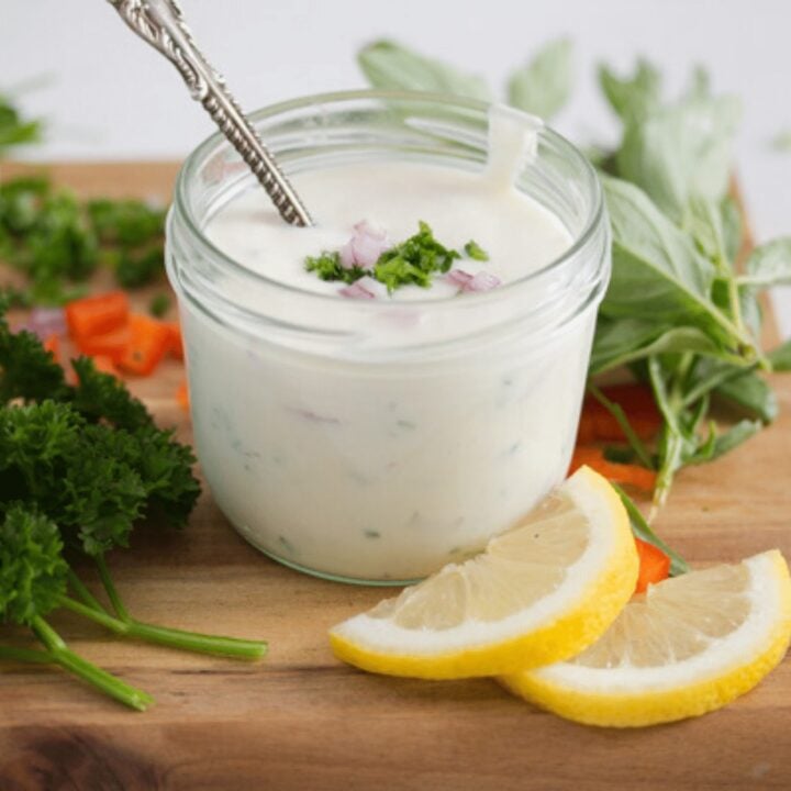 yogurt dressing for salad in a small bowl with lemon slices