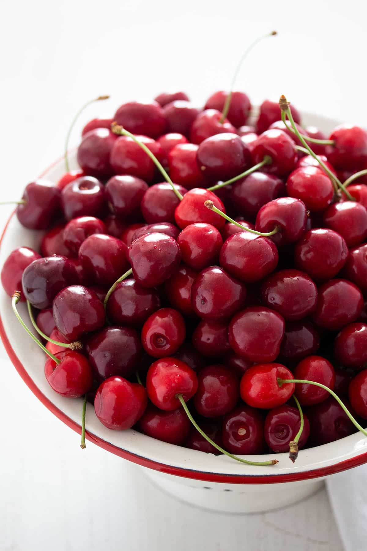 lots of fresh sweet cherries in a large vintage sieve.