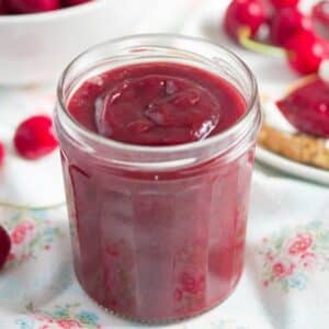 small jar full of smooth cherry butter.