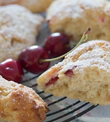 scone showing the crumb and three cherries on a rack.