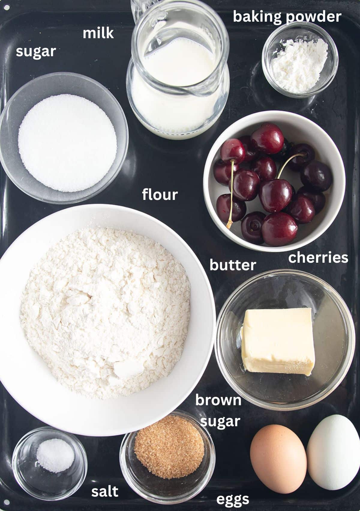 labeled ingredients for making scones with fresh cherries, flour, butter, and eggs.
