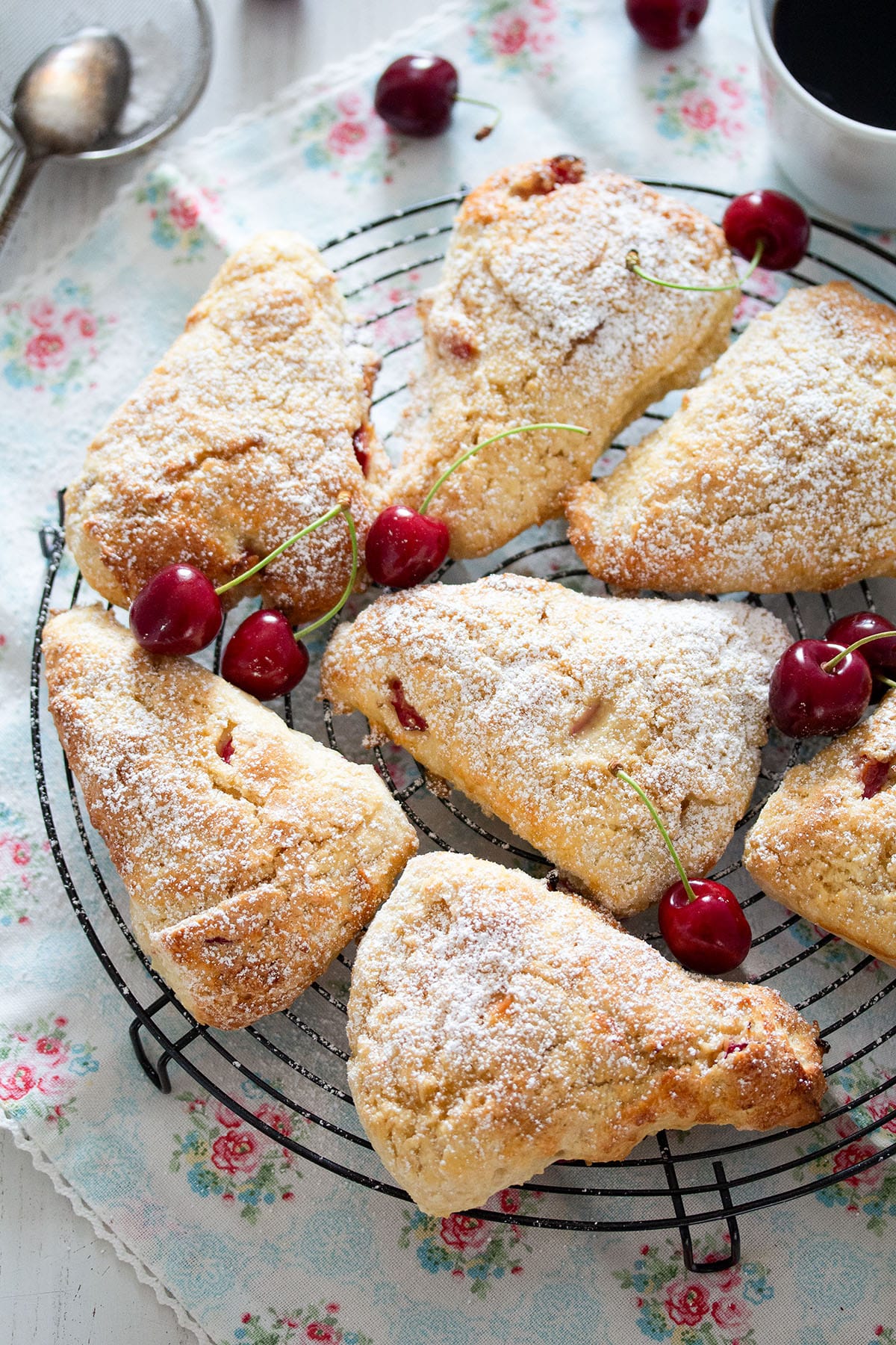 several cherry scones sprinkled with icing sugar on a rack.