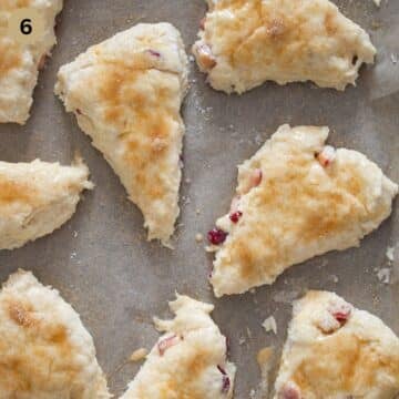 unbaked cherry scones sprinkled with brown sugar on parchment paper.