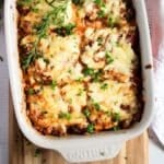 ground beef and zucchini casserole in a baking dish garnished with fresh herbs.