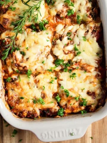 ground beef and zucchini casserole in a baking dish garnished with fresh herbs.