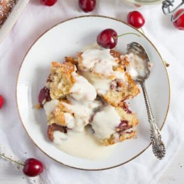 kirschmichel served with vanilla sauce on a small vintage plate with a spoon and cherries around it.