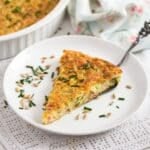 zucchini slice topped with sunflower seeds and chives on a small plate.
