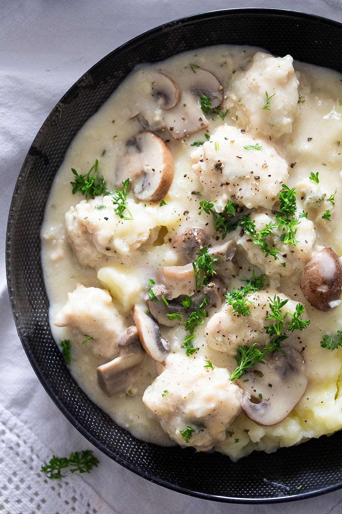 creamy sauce with chicken meatballs and mushrooms served with potato mash in a large bowl.