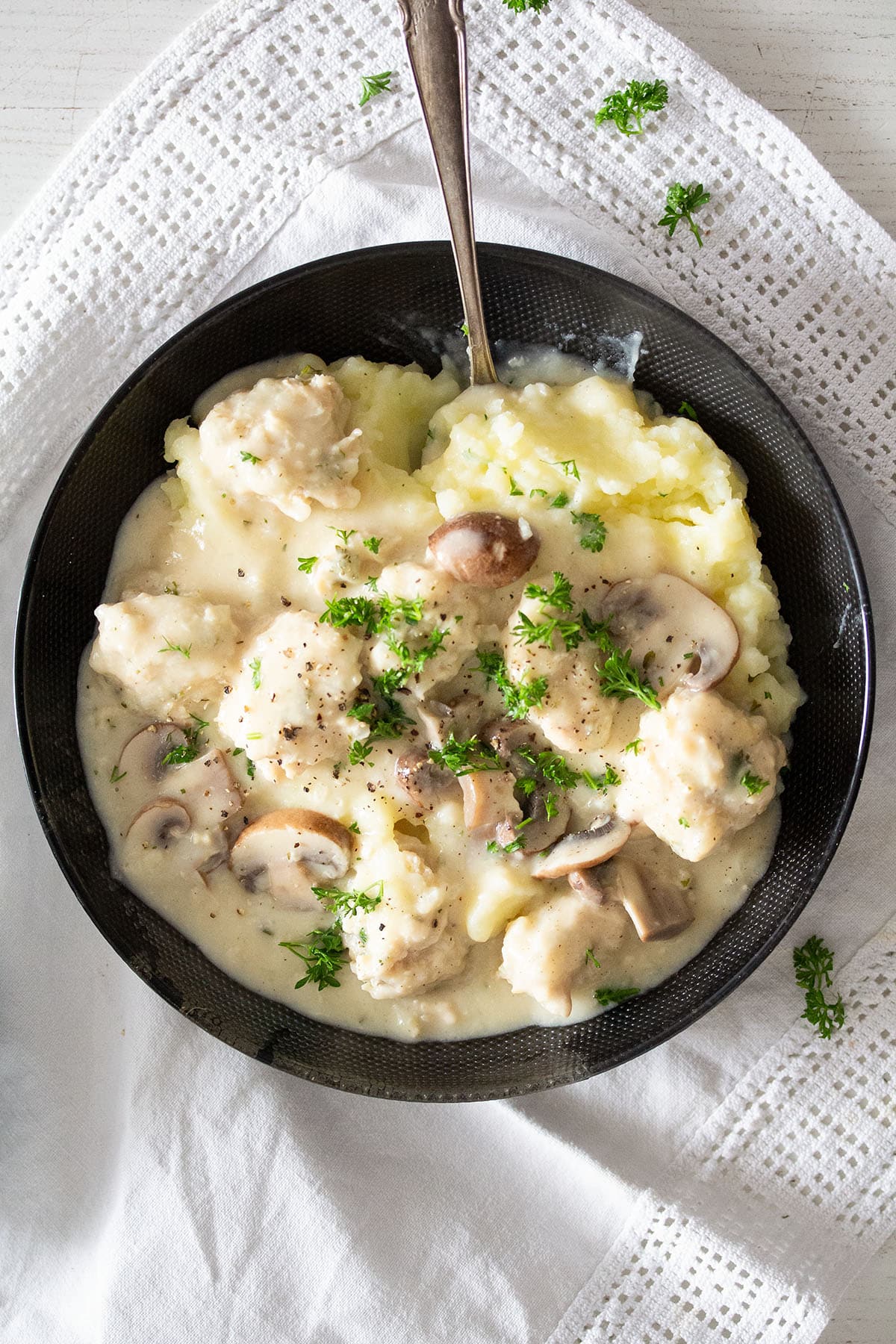 chicken meatballs in creamy sauce with mashed potatoes in a bowl.