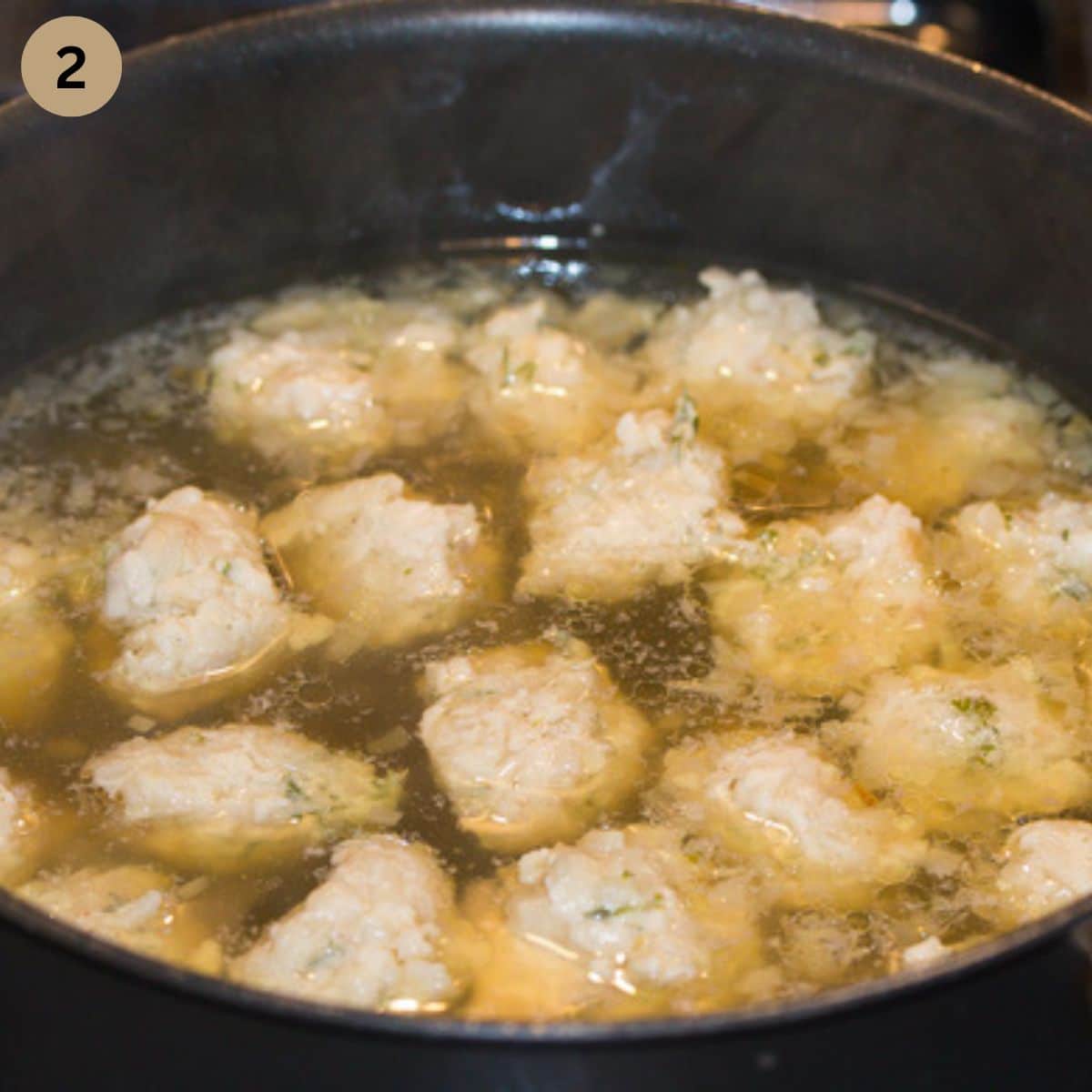 chicken meatballs simmering in chicken broth.