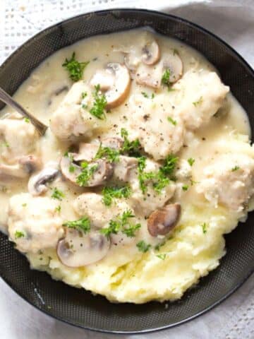 chicken meatballs in creamy sauce served with mashed potatoes in a black bowl.