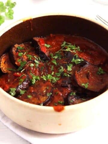 eggplant in tomato sauce in small dish with parsley on top.