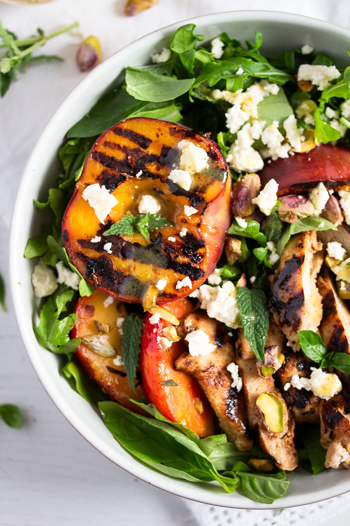 grilled peach salad with chicken breast, arugula, feta and pistachios.