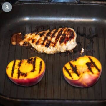 two grilled peach halves and one small chicken breast with char marks in a grill pan.