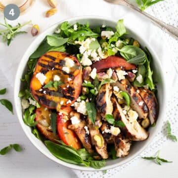 grilled peach salad with chicken and herbs in a bowl.