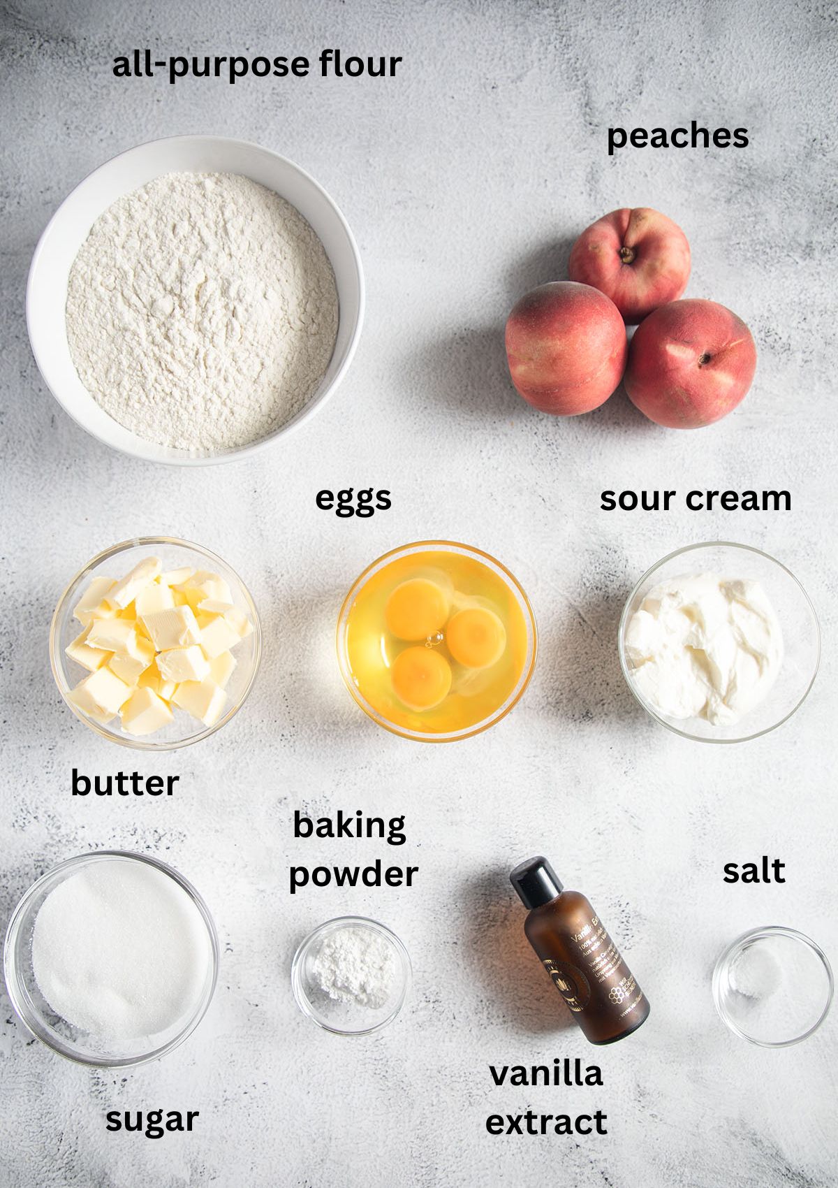 labeled ingredients for making cake with peaches, sour cream, butter, eggs, vanilla, sugar, and flour.