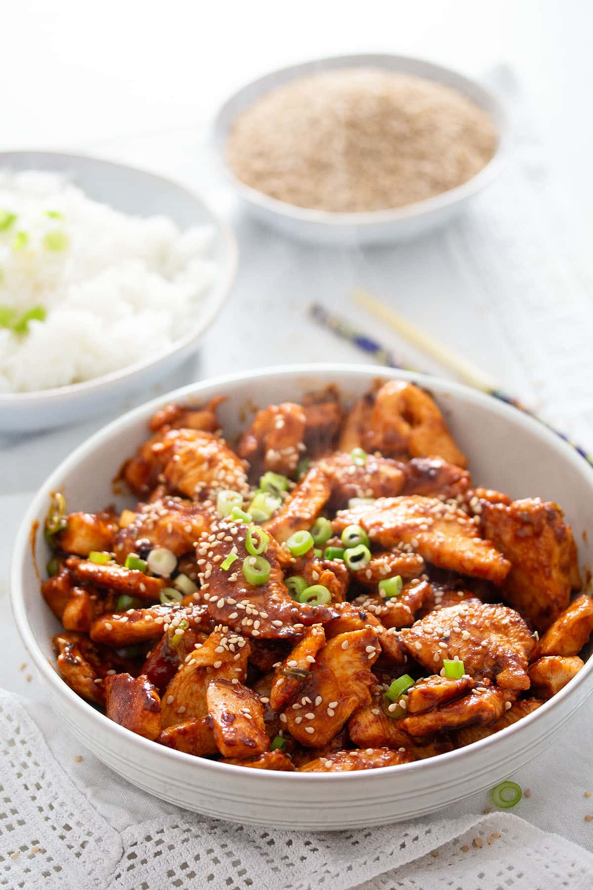 a bowl of gochujang chicken breast, one with rice and one with sesame seeds.