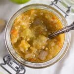 green tomato salsa verde in a small jar with a spoon in it.