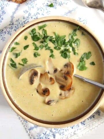 healthy mushroom soup without cream topped with parsley in a small clay pot.