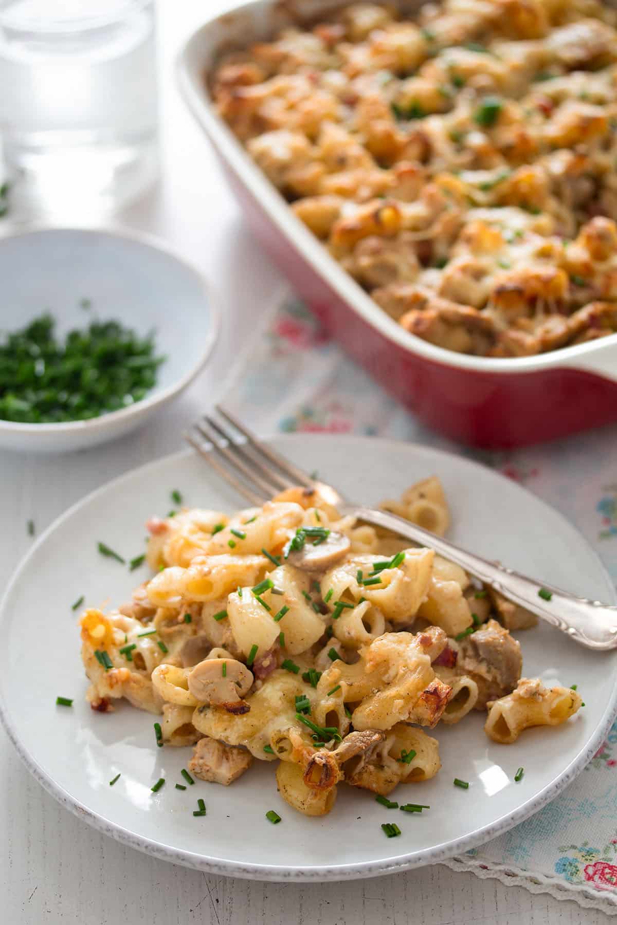 pasta bake with leftover chicken piled on a plate and in a baking dish behind.