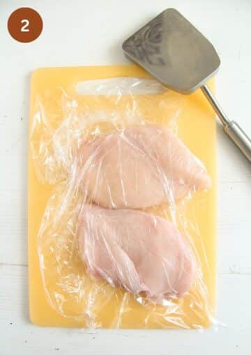 pounding chicken breast covered with clingfilm with a meat mallet.