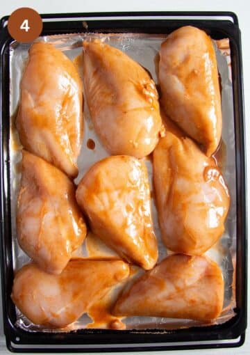 raw chicken breast pieces brushed with marinade on a baking sheet. 