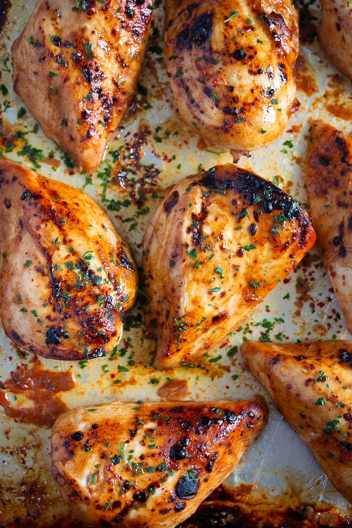 baked bbq chicken breast slightly charred and sprinkled with parsley.