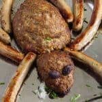 halloween spider meatloaf idea with sausage legs on a platter.