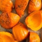 many roasted pumpkin halves on a baking sheed lined with brown parchment paper.