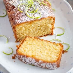 sliced, moist lime drizzle cake and lime zest on a vintage platter.