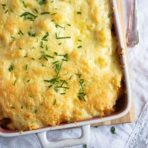 cheesy potato and cabbage bake in a baking dish sprinkled with chives.