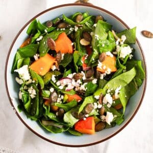 bowl of roast pumpkin salad with feta, spinach, and seeds.