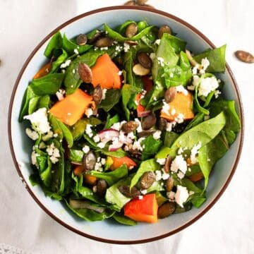 pumpkin seed salad with roasted pumpkin, spinach and feta in a bowl.