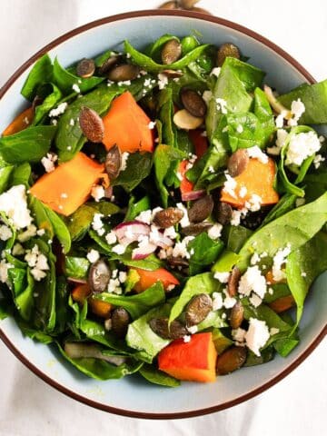 bowl of roast pumpkin salad with feta, spinach, and seeds.
