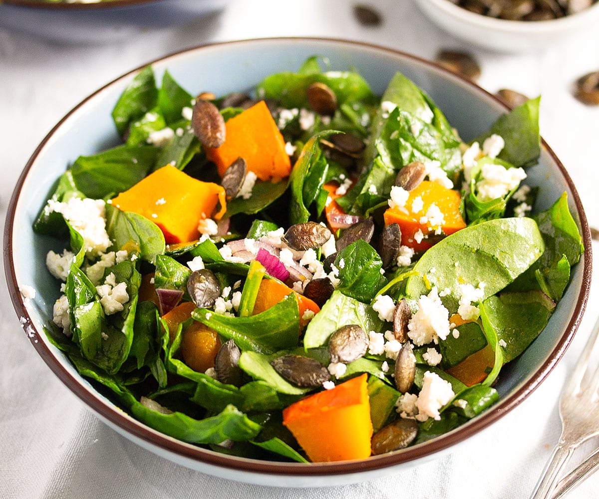 small bowl of salad with chopped spinach, roasted pumpkin, crumbled feta and pepitas.