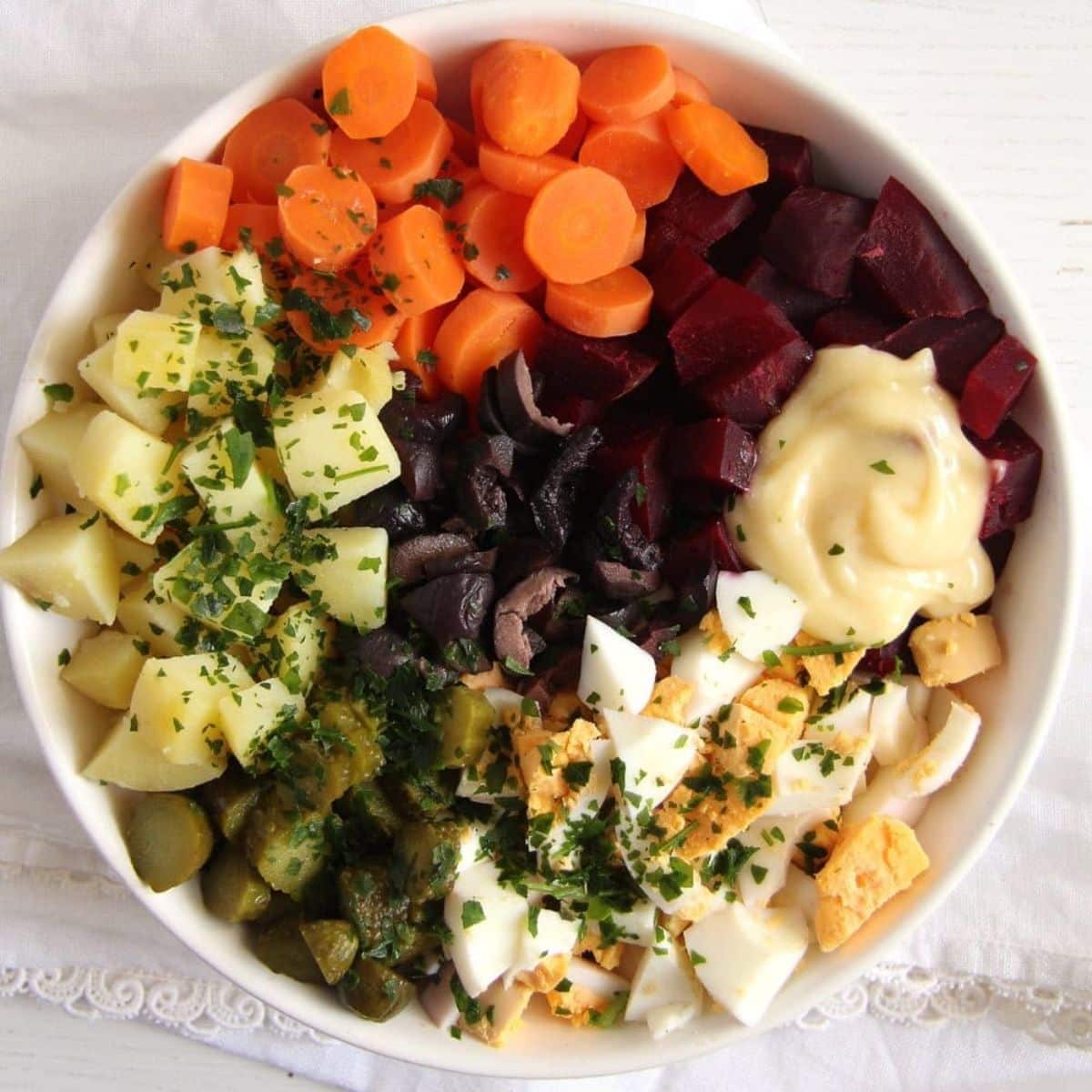 salad russe with carrots, potatoes, beets, eggs, olives and mayonnaise.
