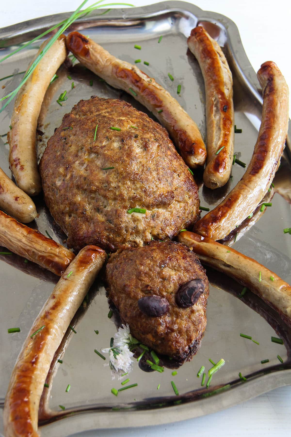spider shaped meatloaf with long sausage legs and olive eyes for halloween.